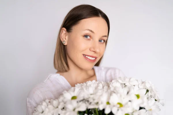 年轻美丽可爱可爱可爱的微笑的女人 手持一束白墙背景的白花 — 图库照片