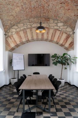 Modern bir ofis, konferans odası, içi ahşap bir masa ve pencerelerin altında duran sandalyeler. Büyük tavan ışığı.