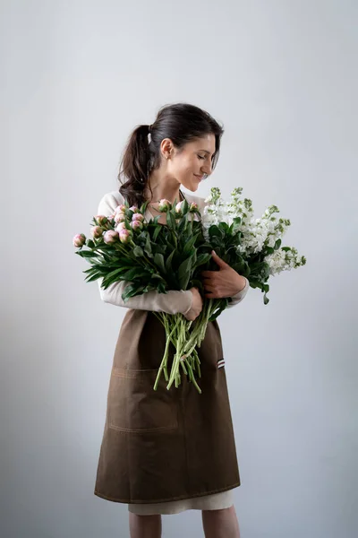 Kobieta Kwiaciarnia Embracing Kilka Białych Różowych Kwiatów Białym Tle Wewnątrz — Zdjęcie stockowe