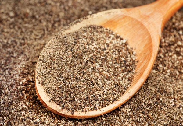 Ground black pepper (Piper nigrum) with wooden spoon — Stock Photo, Image