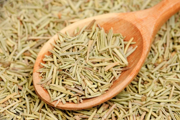 Rosemary in wooden spoon and over as background — Stock Photo, Image