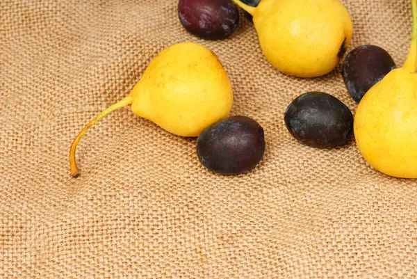 Sommige peren en pruimen op jute achtergrond — Stockfoto