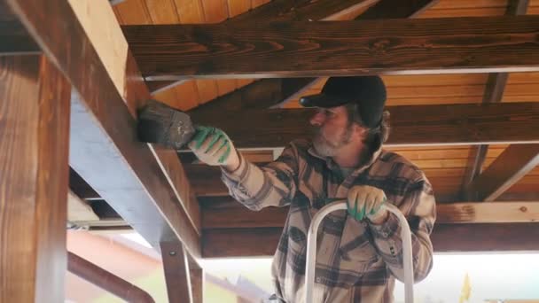 Painter applies paint with a brush to a wooden structure. — Stock Video