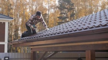 Roofer, çatı vidasını metal çatıya sıkıştırmak için tornavida kullanıyor..