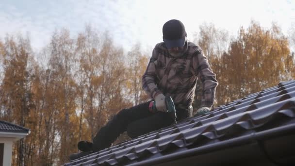 Dachdecker zieht mit einem Schraubenzieher die Dachschraube in das Metalldach. — Stockvideo