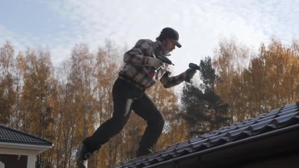 Roofer with two screwdrivers walking on a metal roof without insurance. — Stock Video