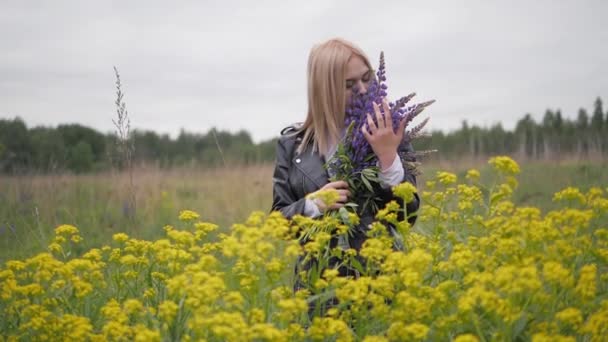 La donna abbraccia delicatamente il bouquet e annusa la fragranza dei fiori. Fiori di colza in natura. — Video Stock