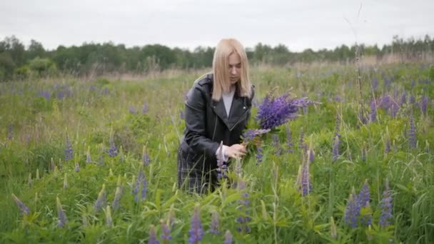 En ung jente på et jorde. Kvinnen omfavner forsiktig en blomsterbukett. – stockvideo