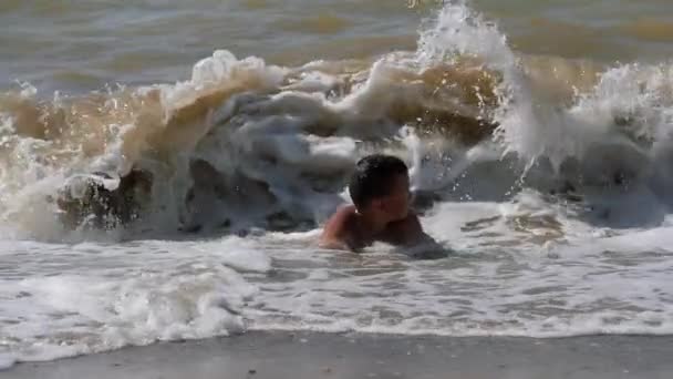 Ondas costeiras do mar a criança mergulha neles. — Vídeo de Stock