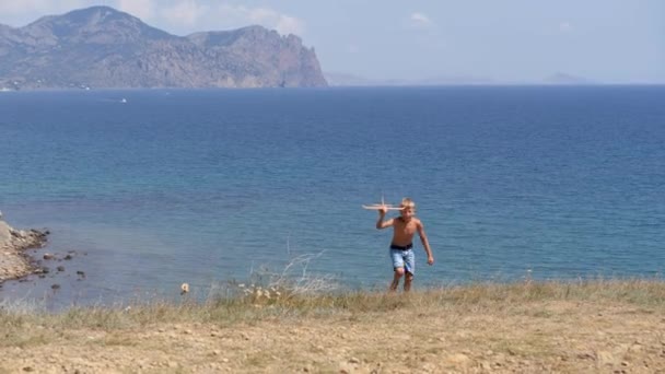 Menino com um avião de brinquedo em suas mãos no fundo do mar. — Vídeo de Stock