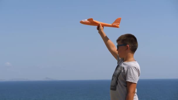 바다 배경에 손에 장난감 비행기를 들고 있는 소년. — 비디오