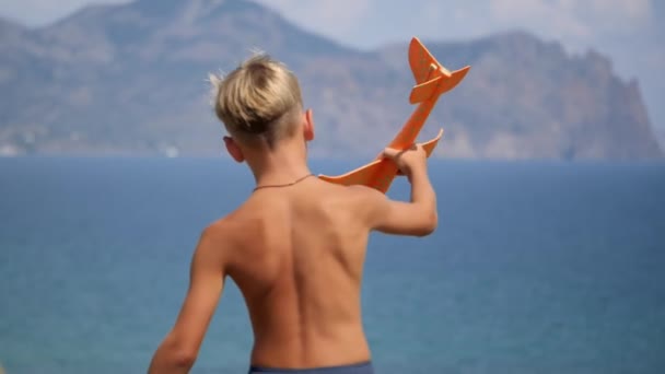 Хлопчик з іграшковим літаком в руках на тлі моря . — стокове відео