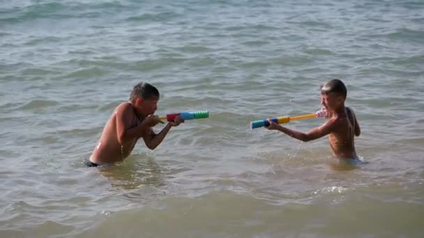 Kinderen spelen met waterpistolen in de zee. — Stockvideo