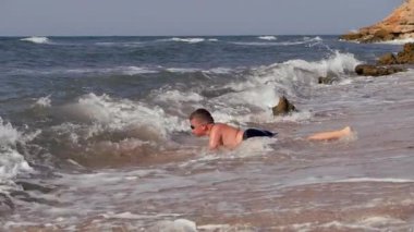 Kıyıdaki deniz dalgaları çocuğun dalmasına neden oluyor..