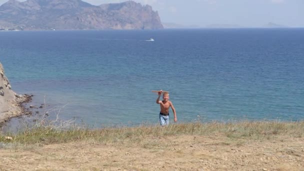 Jongen met een speelgoed vliegtuig in zijn handen op de achtergrond van de zee. — Stockvideo