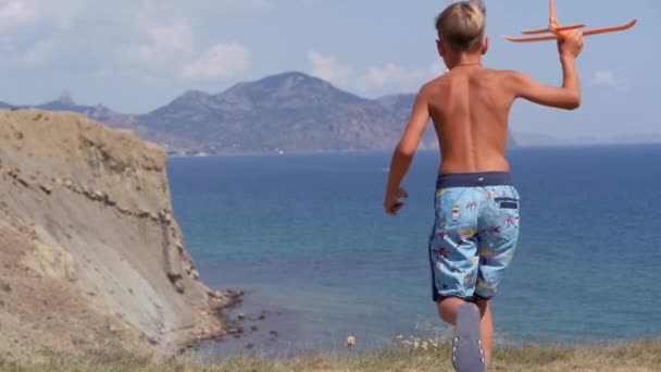 Jongen met een speelgoed vliegtuig in zijn handen op de achtergrond van de zee. — Stockvideo