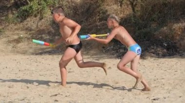 Çocuklar deniz sahilinde su tabancalarıyla oynuyorlar..