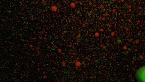 Oranje en groen volumetrische fluorescerende deeltjes bewegen en veranderen op een zwarte bewegende achtergrond, overgang. — Stockvideo