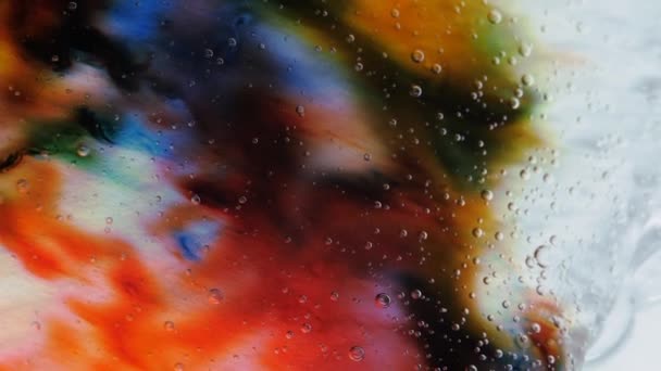 Прозора космічна рідина заповнена краплями червоної, синьої, жовтої та зеленої фарби . — стокове відео