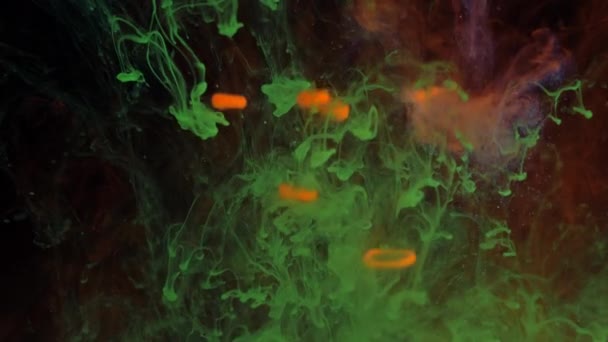 Mélange de particules de couleurs éclatantes de peinture verte et rouge en fumée. — Video