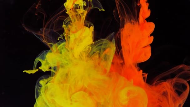 Stream of red and yellow paint dissolves in a transparent space on a black background. — Stock Video