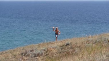 Denizin arka planında oyuncak bir uçağı olan bir çocuk..