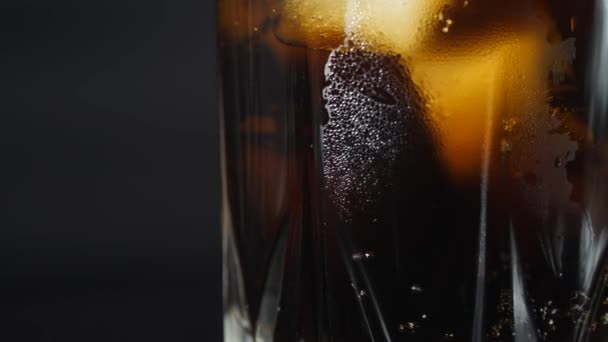 El vaso de hielo está lleno de agua de soda. Verter bebidas carbonatadas oscuras con cubitos de hielo. — Vídeos de Stock