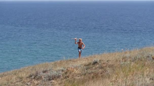 Boy with a toy airplane in his hands on the background of the sea. — Stock Video