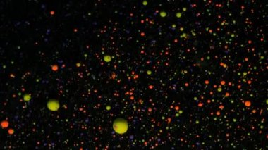 Siyah arkaplanda gümüş pullu yuvarlak renkli toplar. Kırmızı ve sarı parçacıklar rastgele hareket eder.