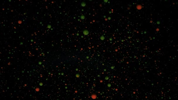 Okrągłe kolorowe kulki na czarnym tle ze srebrnymi cekinami. Czerwone i zielone cząstki poruszają się losowo. — Wideo stockowe