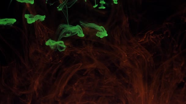 Mixing particles of glowing colors of green and red paint in smoke. — Stockvideo
