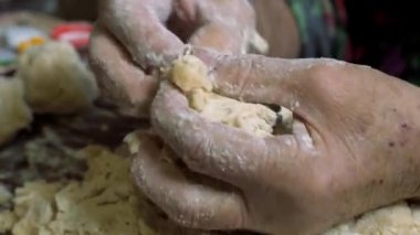 Yaşlı bir adamın buruşuk elleri hamuru yoğurur ve kolobok topları yapar..