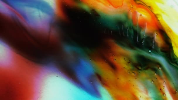 Transparent space liquid is filled with drops of red, blue, yellow and green paint. — Stockvideo