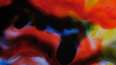 Şeffaf uzay sıvısı kırmızı, mavi, sarı ve yeşil boya damlalarıyla doludur..