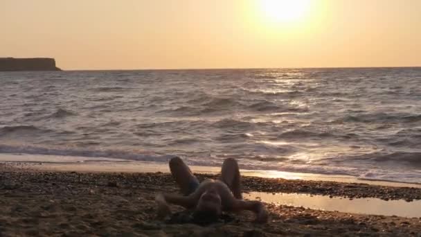 Gün batımının arka planında yoga yapan bir çocuk figürü.. — Stok video
