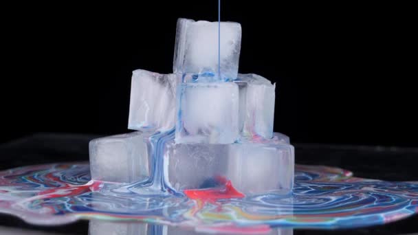 Farba wielobarwna rozprzestrzenia się po powierzchni kostek lodu i spływa na płaszczyznę. — Wideo stockowe