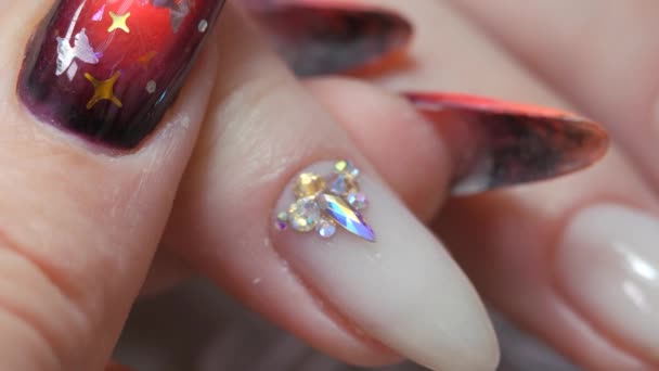 Applying a three-dimensional pattern with rhinestones and broths on the nail. — Stock Video
