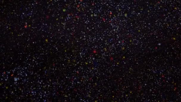 Sequins op een zwarte achtergrond. Sprankelende deeltjes bewegen chaotisch. Kerstmis, Nieuwjaar screensaver. — Stockvideo