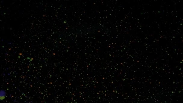 Круглі різнокольорові кульки на чорному тлі зі срібними блискітками. Червоні, сині та зелені частинки рухаються випадково . — стокове відео