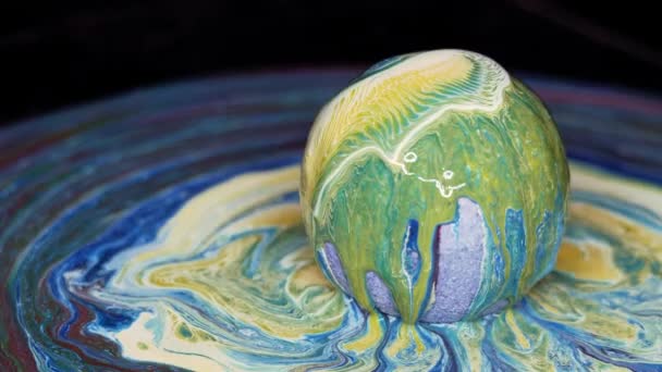 Farbe fließt über die Oberfläche des Texturballs und breitet sich über den Tisch aus. — Stockvideo