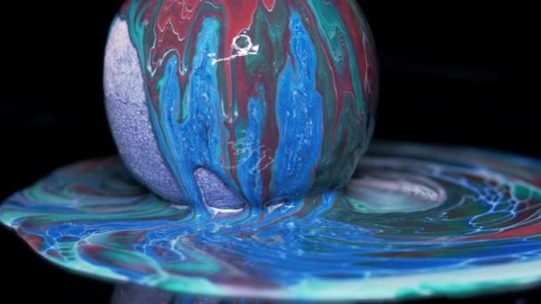 Farbe fließt über die Oberfläche des Texturballs und breitet sich über den Tisch aus. — Stockvideo