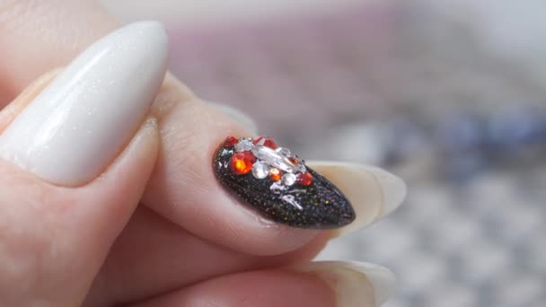 Applying a three-dimensional pattern with rhinestones and broths on the nail. — Stock Video