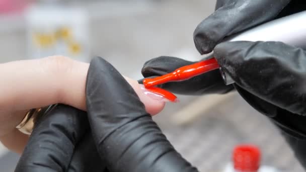 Εφαρμόζοντας ένα στρώμα κόκκινου βερνικιού στην επιφάνεια των νυχιών. — Αρχείο Βίντεο