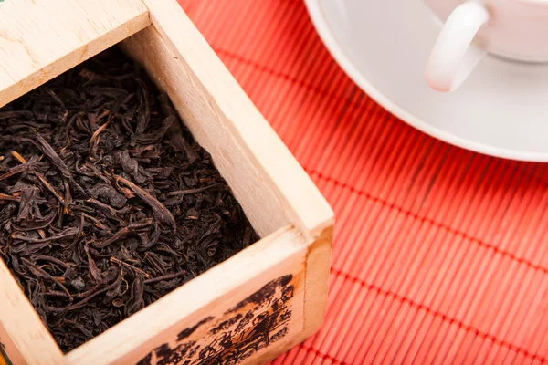 Box with black tea on red mat — Stock Photo, Image