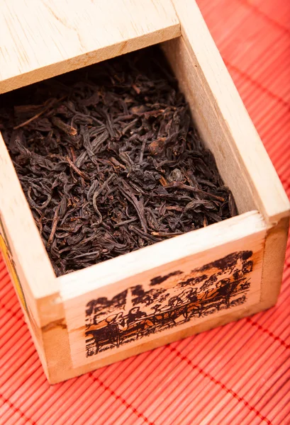 Caixa com chá preto no tapete vermelho — Fotografia de Stock