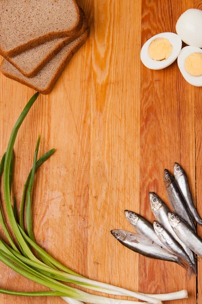 Ikan asin, telur, roti dan bawang musim semi di kayu — Stok Foto