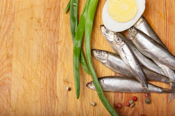 Anchovas salgadas, ovo e cebolinha em madeira — Fotografia de Stock