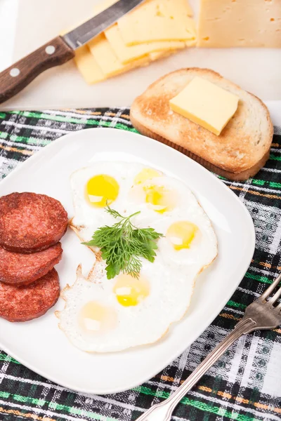 Frühstück mit Spiegeleiern, Wurst und Toast auf Teller — Stockfoto