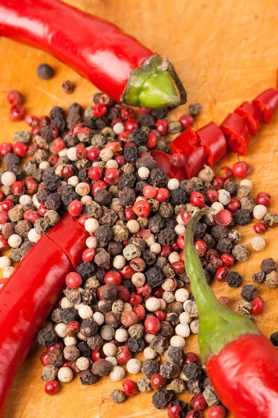 Cut capsicum chili pepper and peppercorn on wooden board — Stock Photo, Image