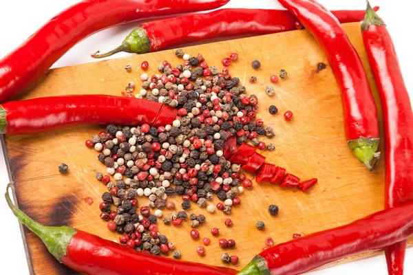 Skär paprika chilipeppar och pepparkorn på träskiva — Stockfoto